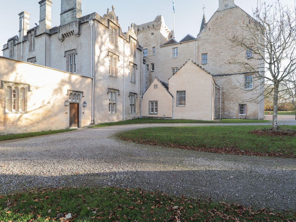 A courtyard with gravel paths and a tree next to historic stone buildings at The Laird's Wing - Brodie Castle in Forres