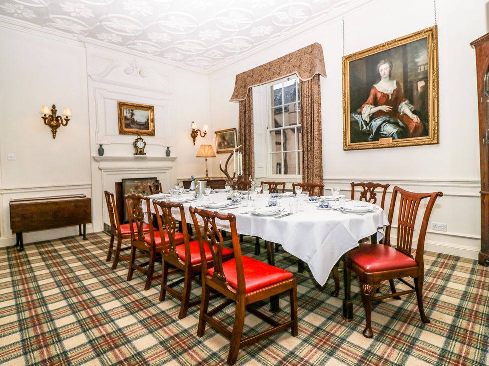 A dining room with a table set for dinner and wooden chairs with red seats at The Preston Tower Apartment - Fyvie Castle in Rothienorman