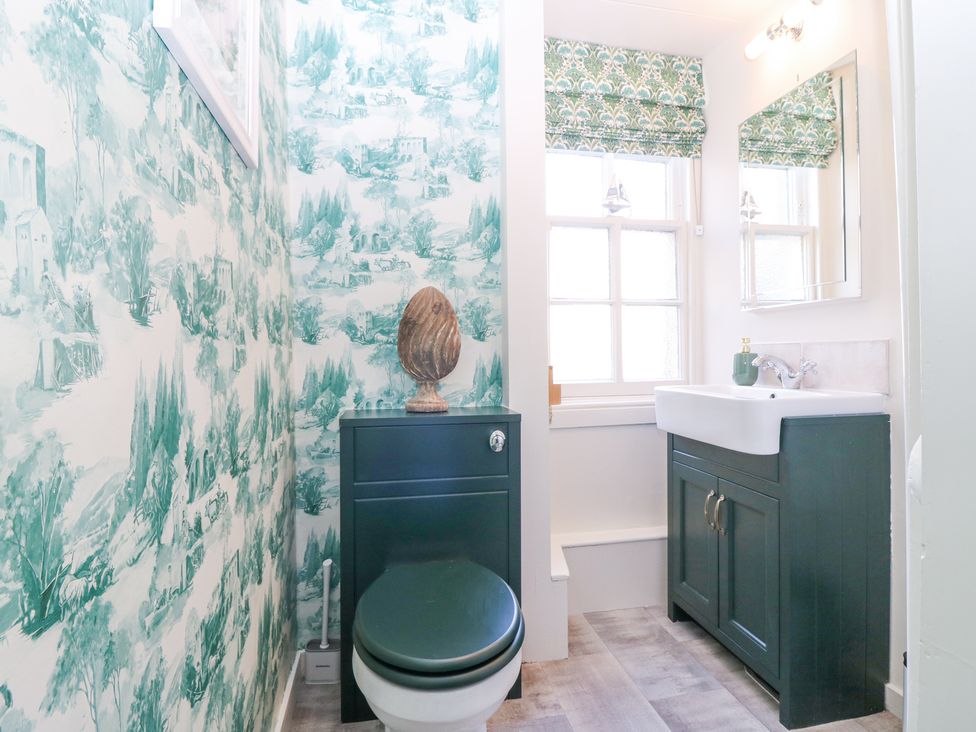 A bathroom with a green toilet and vanity unit with a white sink and a window with patterned blinds at North Wing - Pitmedden Gardens in Pitmedden