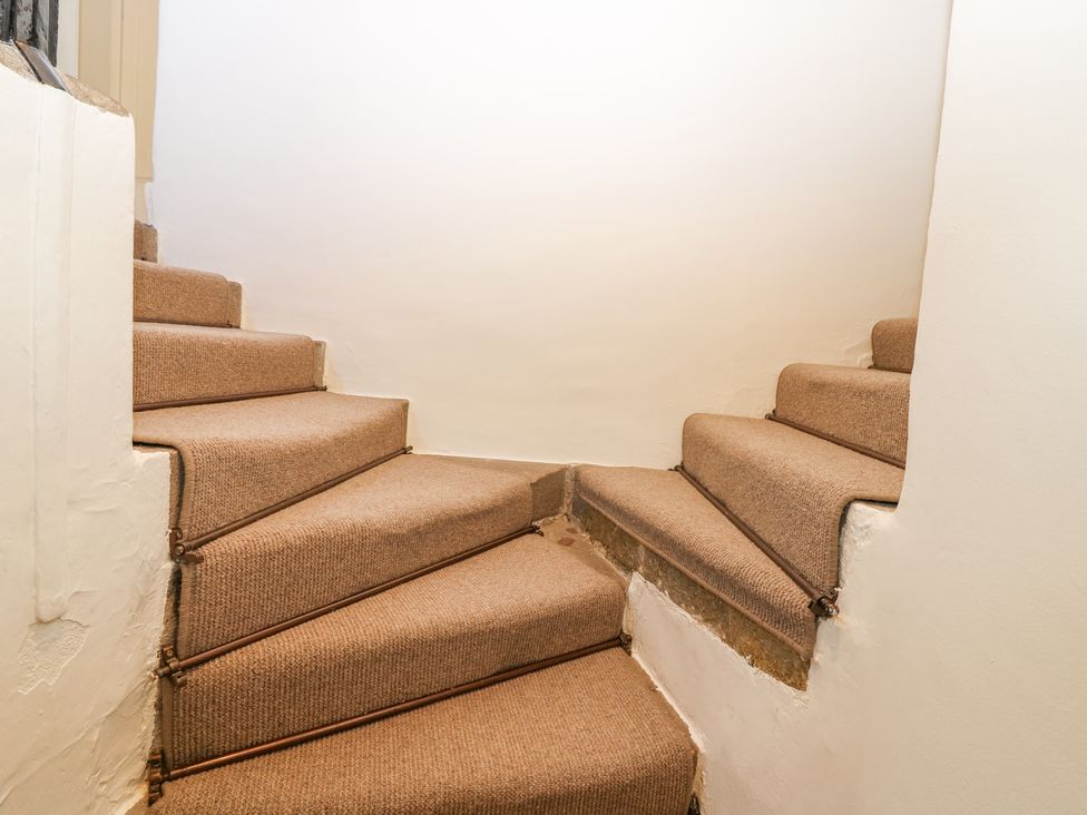 Carpeted stairs with metal rods on the edges in a stairwell with white walls at North Wing - Pitmedden Gardens in Pitmedden