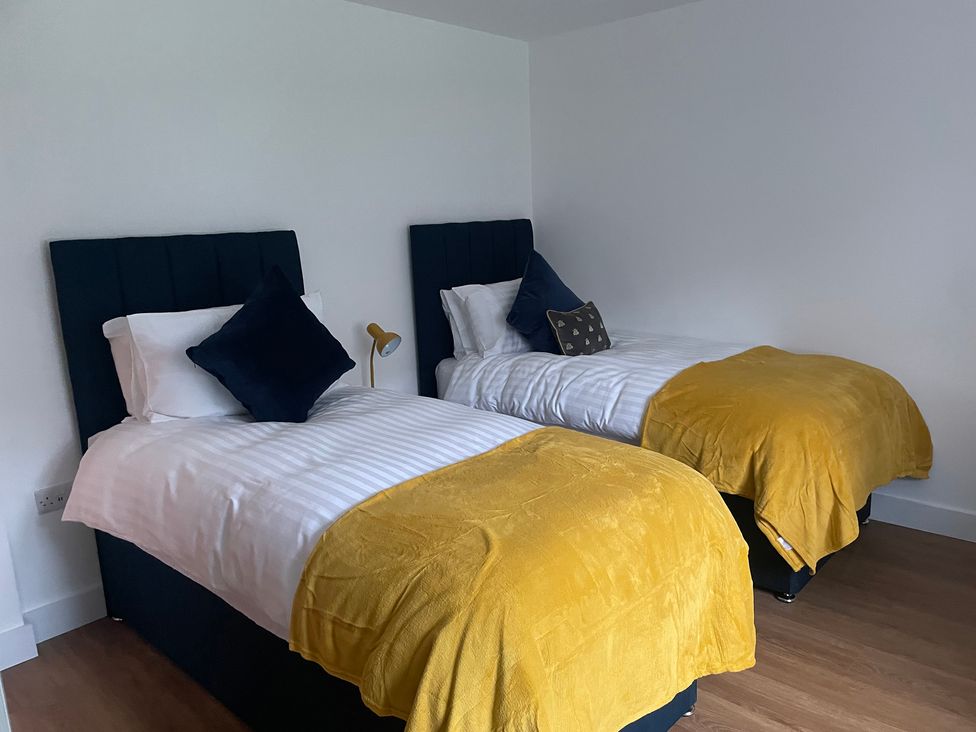 A bedroom with two single beds with yellow throws and dark headboards at Pennant Uchaf in Pennant near Llanbrynmair