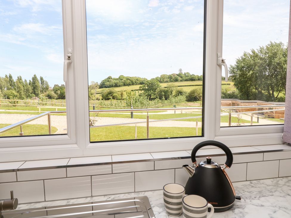 A kitchen window with a view of a garden and countryside with a kettle and two mugs on the countertop at Chianti in Seaview