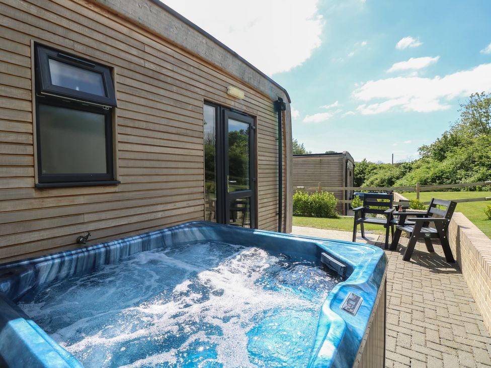 An outdoor patio with a hot tub and two wooden chairs beside a wooden house at Chianti in Seaview