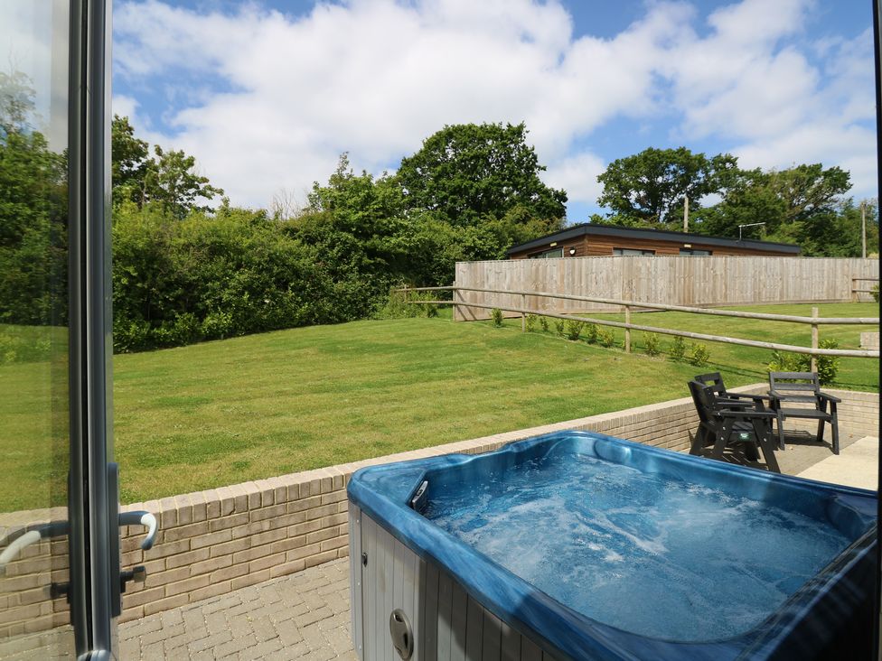 A garden with a hot tub and outdoor chairs near a wooden fence and trees at Chianti in Seaview