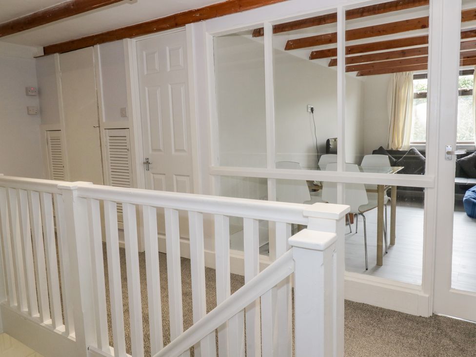 A hallway with white railings and doors looking into a dining area with a table and chairs at Waters Edge in Stranraer