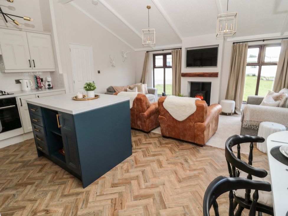 A kitchen and living room with an island unit leather armchairs sofas and a fireplace at The Treeline in Swarland near Felton