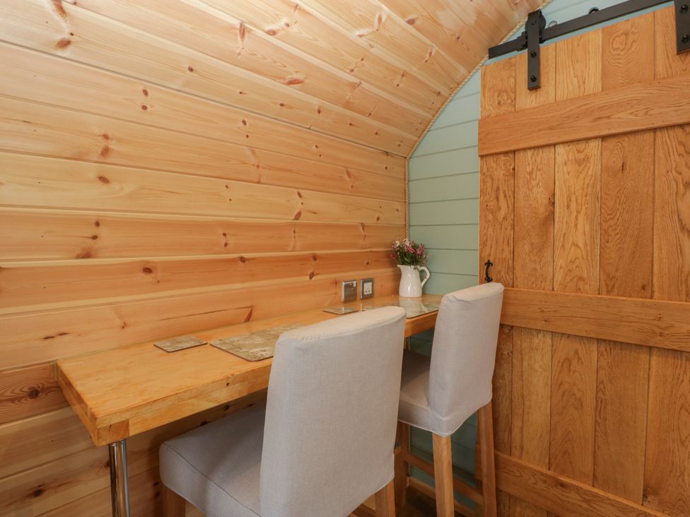 A wooden table with two high chairs and a sliding wooden door in a small room at Dew Pond in Blagdon