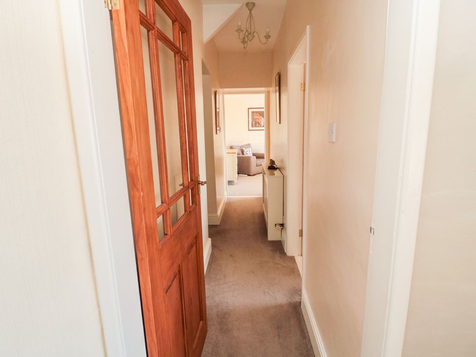A hallway with a wooden door partially open leading to a room with a chair at Healey Farm Cottage in Rothbury