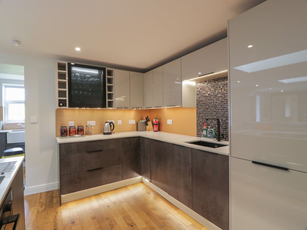 A kitchen with brown lower cabinets white upper cabinets and a black sink at Hardhills Cottage in Castle Douglas