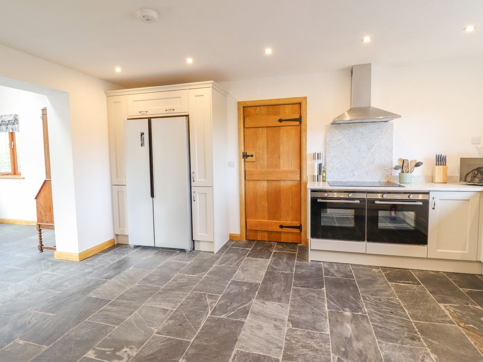 A kitchen with a double door refrigerator a wooden door double ovens and a stove with a metal hood at Cwmwr in Penybontfawr
