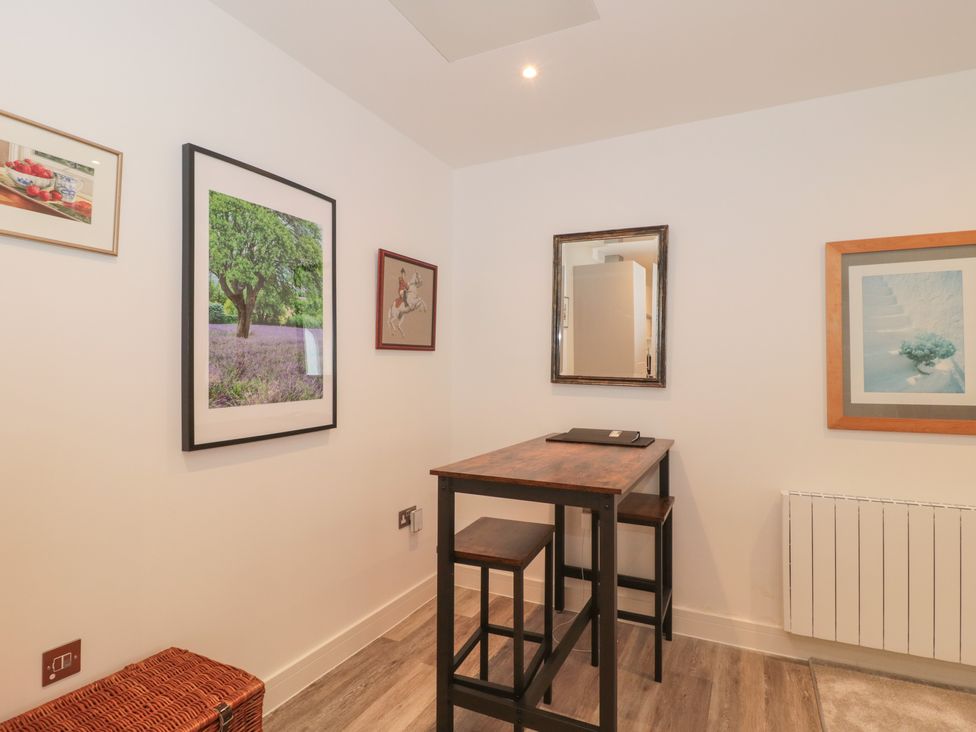 A small dining area with a high wooden table and two stools with framed pictures on the walls at Flat 2 in Bournemouth