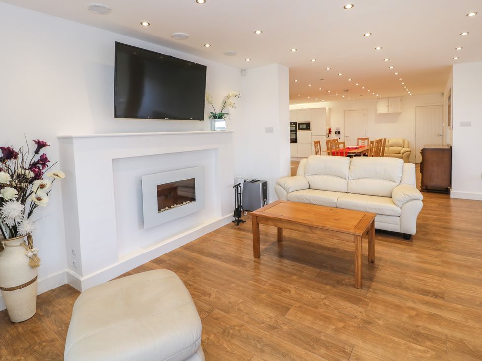 A living room with white sofas wooden coffee table wall mounted tv and fireplace at Top Of The Lane Luxury Holiday Apartment in Benllech