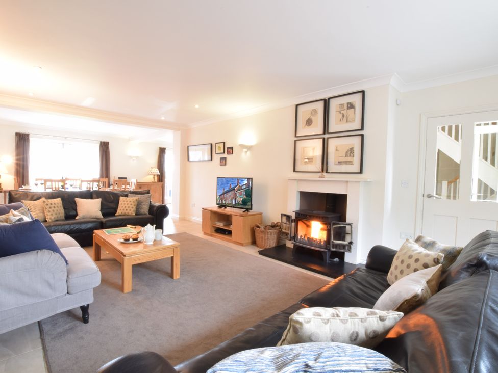 A living room with sofas a coffee table a wood burning stove and a television at Seadrift in Dunwich Near Westleton