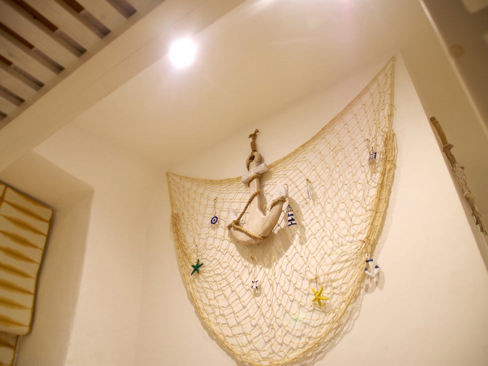 A wall with a nautical net decorated with a large anchor and sea-themed ornaments at Salty Sea Dog in Trebarwith Strand near Tintagel