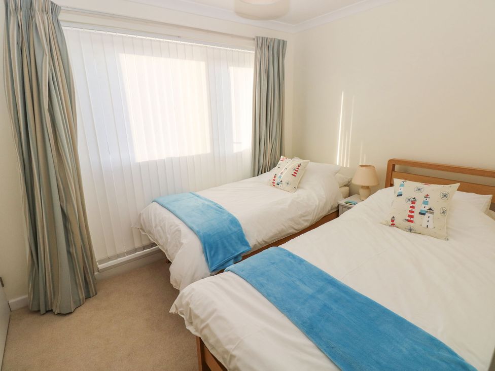 A bedroom with two single beds with white bedding and blue throws at 30 Long Shepherds Drive Newton near The Mumbles