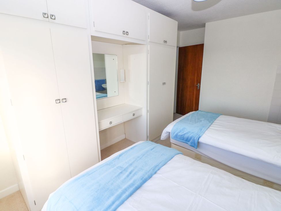 A bedroom with two single beds white wardrobes and a dressing table at 30 Long Shepherds Drive in Newton near The Mumbles