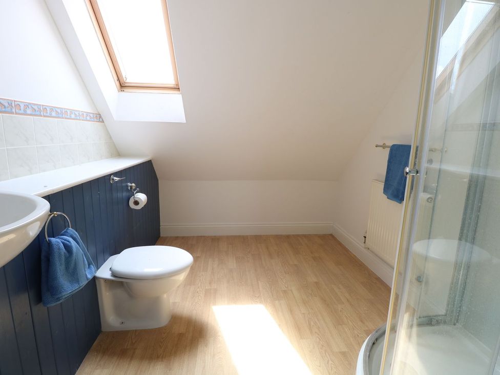 A bathroom with a toilet sink towel rail and shower under a skylight at Drifters in Winterton-On-Sea
