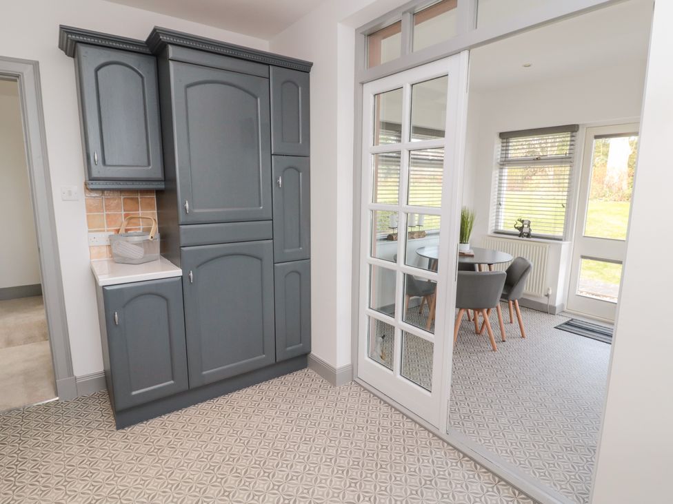 A kitchen area with gray cabinets and a glass door leading to a dining room with a round table and chairs at The Annexe in Berwick-Upon-Tweed