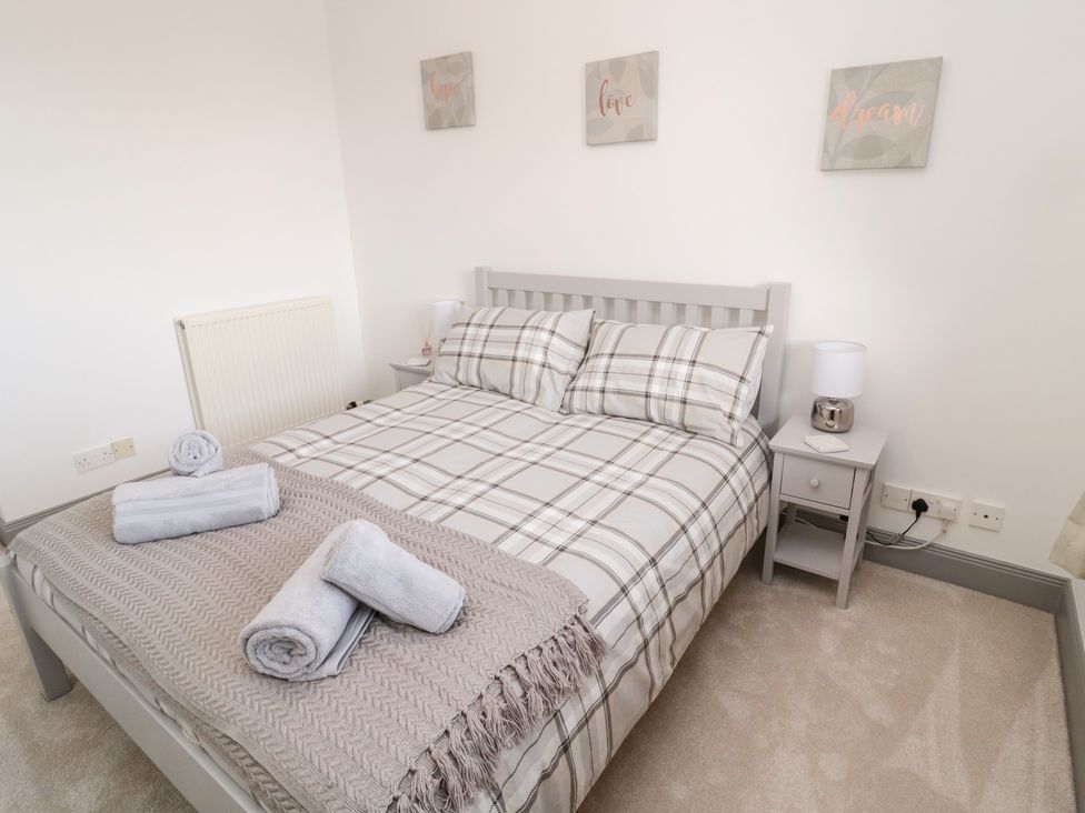 A bedroom with a double bed with plaid bedding and folded towels on top at The Annexe in Berwick-Upon-Tweed