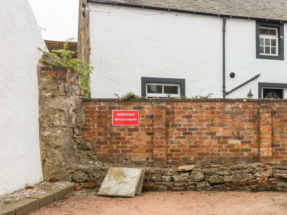 An outdoor area with a brick wall and a red sign reading Rosedale Private Parking in front of a white building at Rosedale in Falkland