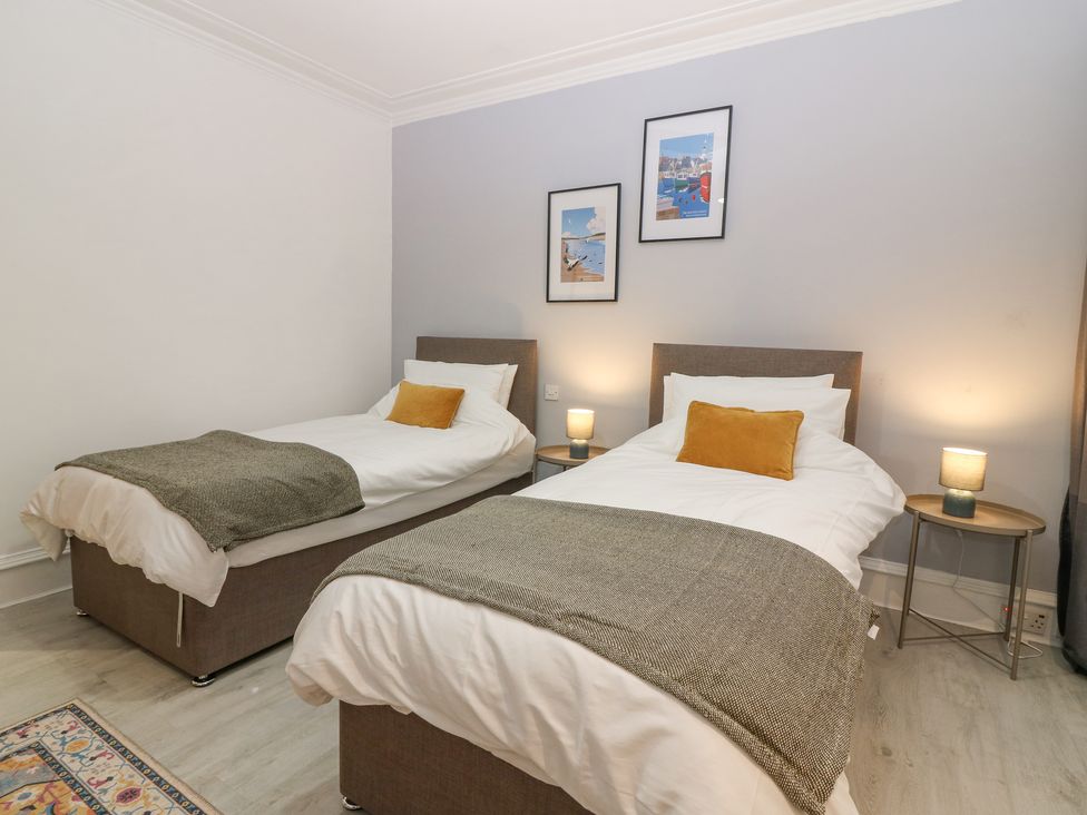 A bedroom with two single beds a bedside table with lamps and pictures on the wall at 16 Main Street Newburgh near Ellon