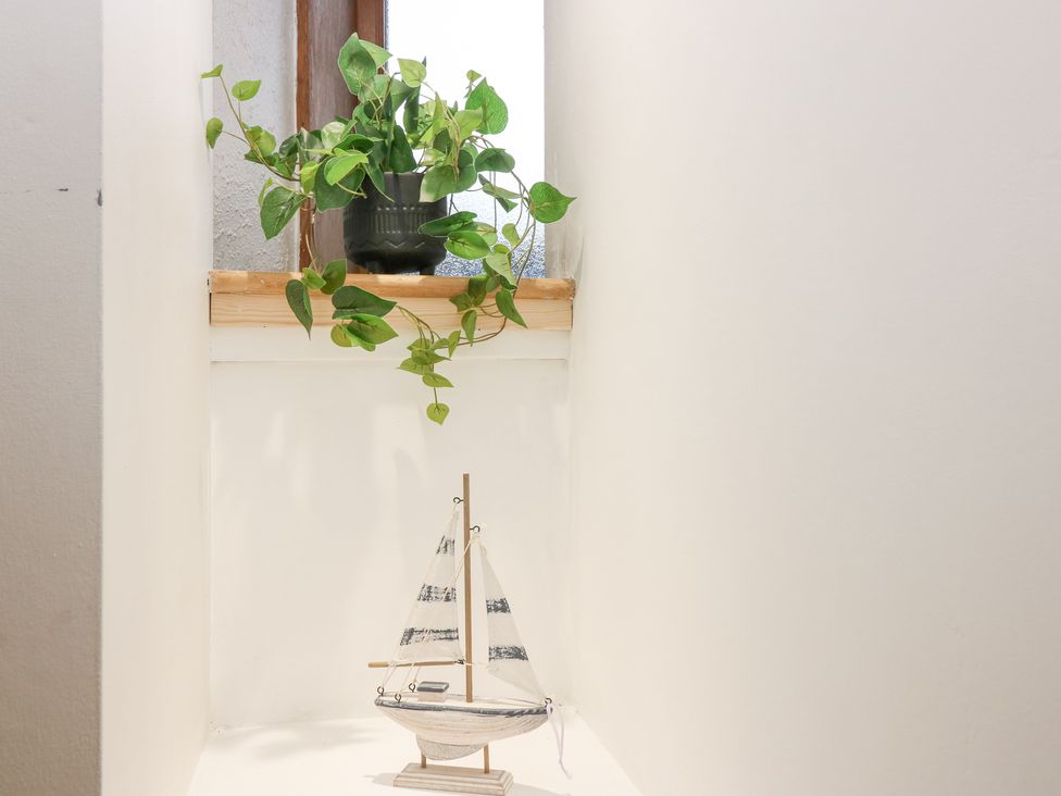 A small sailboat model on a white surface below a window with a green potted plant at 16 Main Street in Newburgh near Ellon