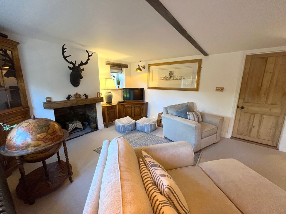 A living room with a beige sofa armchair striped cushions globe and mounted deer head at Old Post Office Sherborne