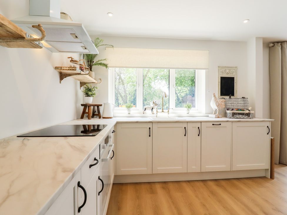 A kitchen with white cabinets and a countertop by a window at Pantiles in Eyke near Woodbridge
