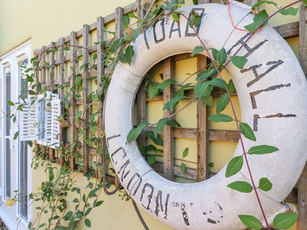 A life preserver mounted on a wooden trellis with green vines on a yellow wall at Pantiles in Eyke near Woodbridge