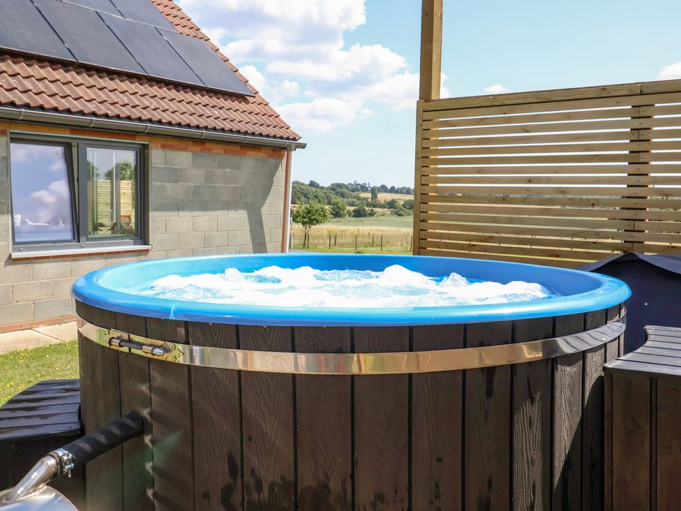 An outdoor hot tub with bubbling water next to a house with solar panels on the roof at Polly's Annexe in Levington