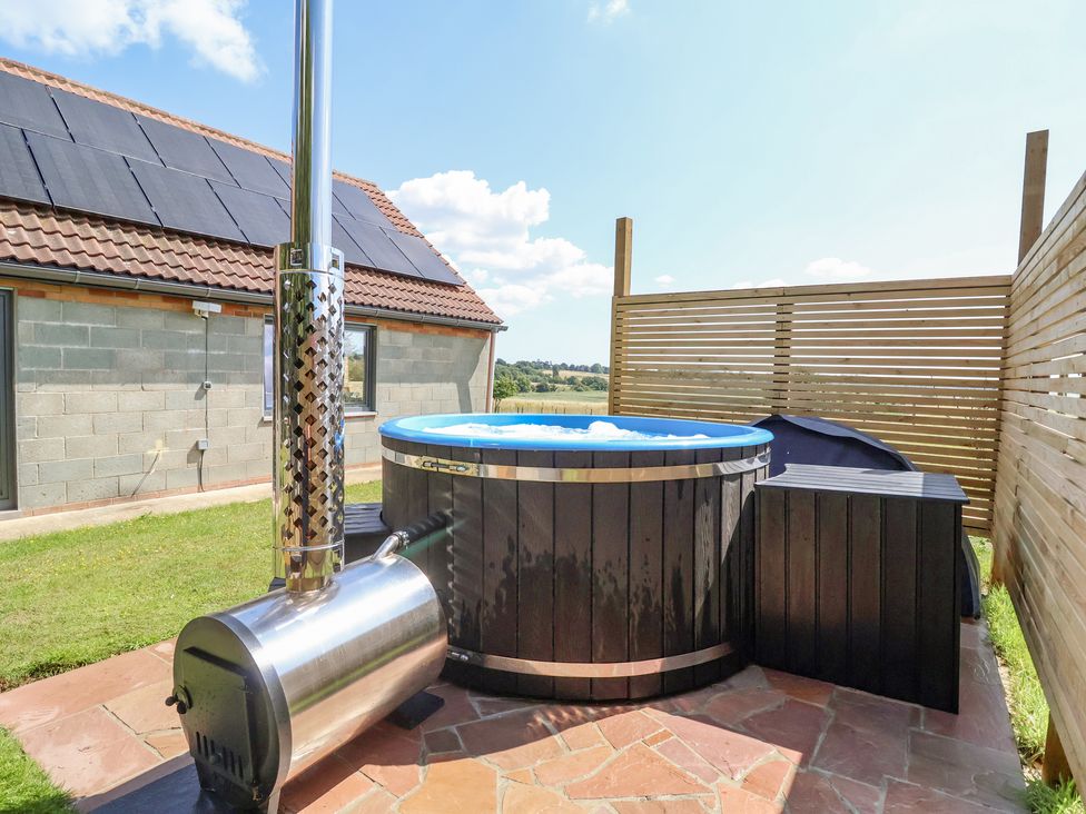 An outdoor hot tub with a stove and wooden privacy screens at Polly's Annexe in Levington