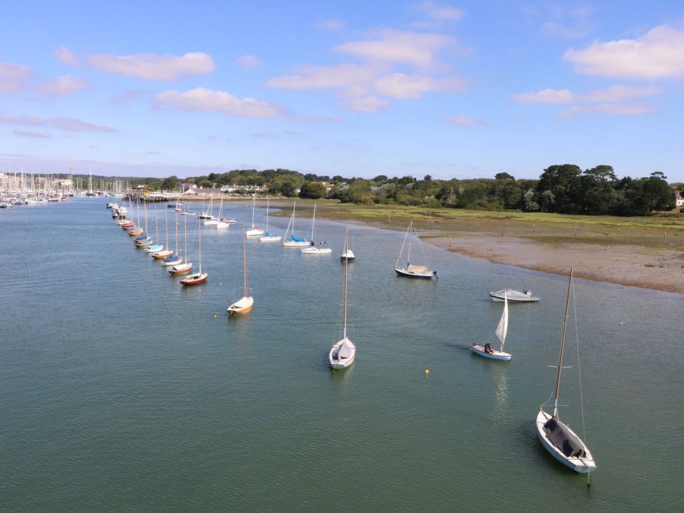 A river with multiple sailboats anchored near the shore and a grassy bank at Cape A1 West Bay Club near Yarmouth