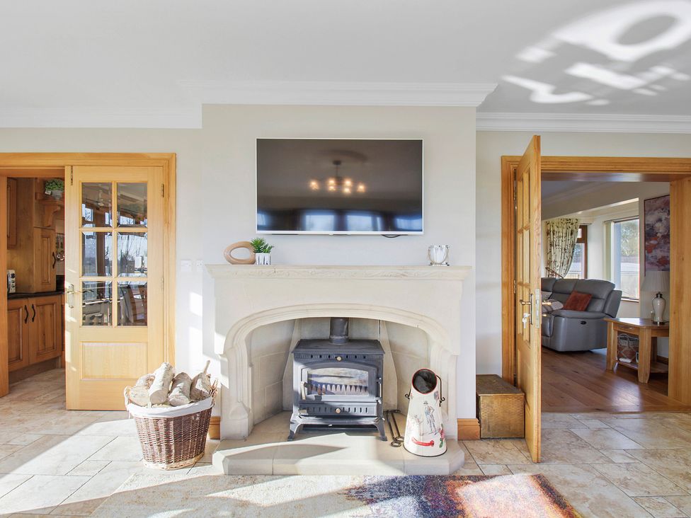 A fireplace with a wood stove and a basket of firewood in a living space at Rose Cottage in Muff County Donegal