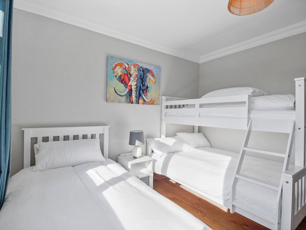 A bedroom with a single bed a bunk bed a nightstand with a lamp and an elephant painting on the wall at Rose Cottage in Muff County Donegal