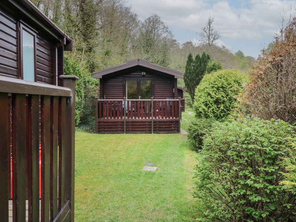 A wooden cabin with a small porch surrounded by grass and bushes at Canadian Cabin No 38 in Keswick