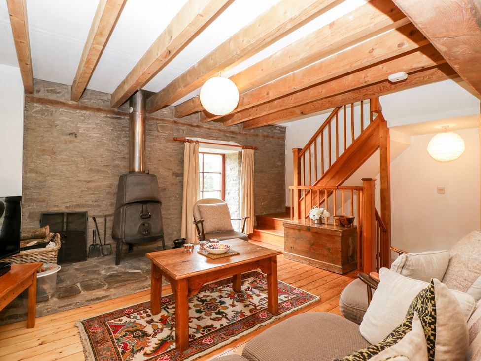 A living room with wooden beams a staircase a fireplace and a wooden coffee table at Halls Mill in Huntington Herefordshire