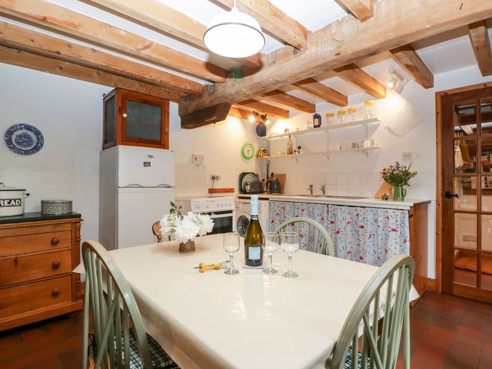 A kitchen with a wooden dining table and chairs a refrigerator stove and wooden ceiling beams at Halls Mill in Huntington Herefordshire