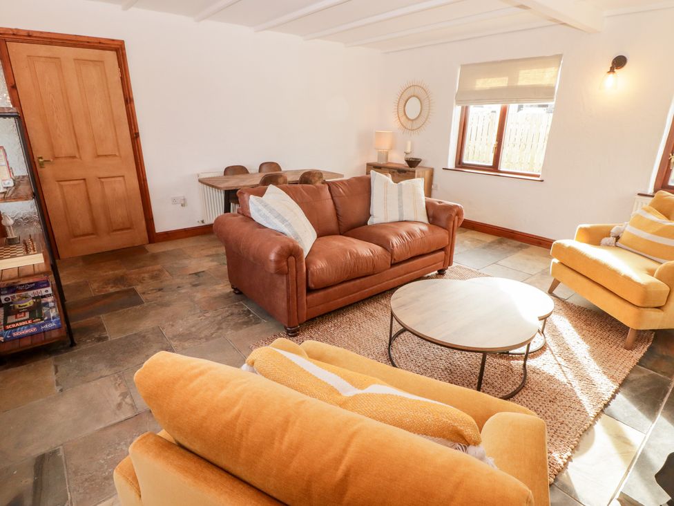 A sitting room with leather and fabric armchairs a round coffee table and a wooden dining table at Fountain Folly in Moylgrove near St Dogmaels