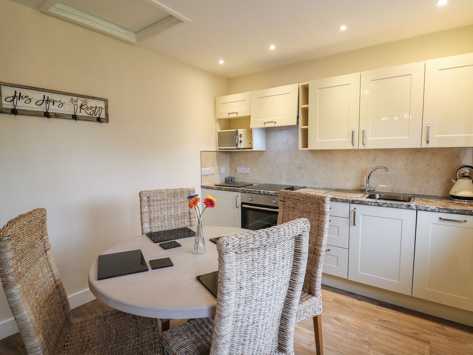 A kitchen with a round dining table and four wicker chairs at Country Cottage in Brecon