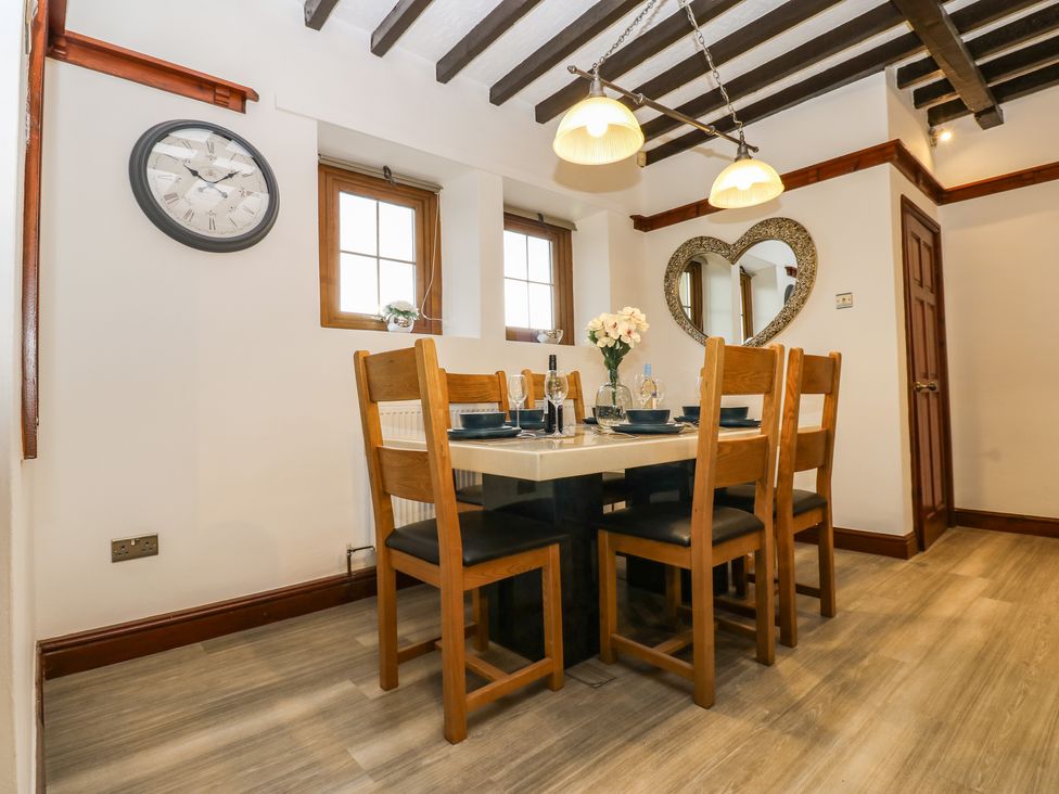 A dining room with wooden chairs around a table and a heart shaped mirror on the wall at Winding Wheel Cottage in Cambois near Ashington