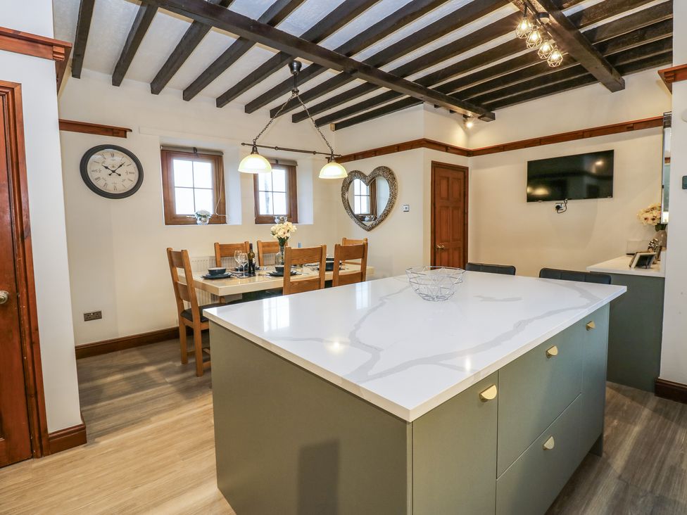 A kitchen and dining area with a large island and dining table with chairs at Winding Wheel Cottage in Cambois near Ashington