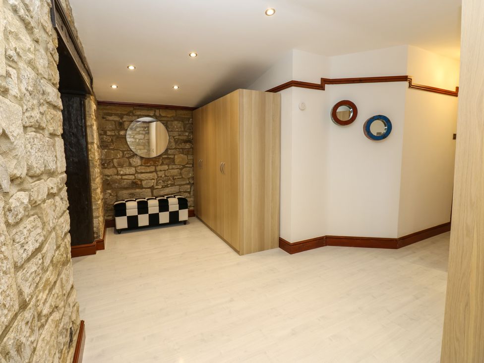 A hallway with stone walls wooden wardrobe checkered bench and round mirrors at Winding Wheel Cottage in Cambois near Ashington
