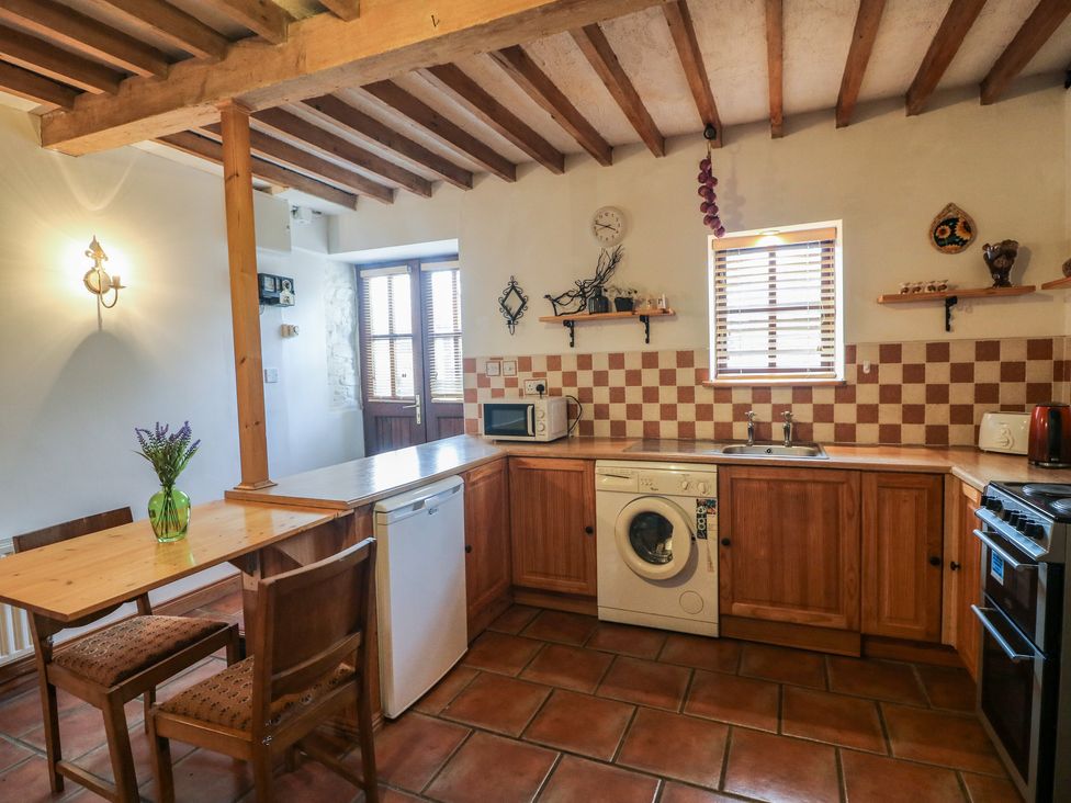 A kitchen with wooden cabinets a dining table with chairs a washing machine and a window at The Abraham in Castledermot County Kildare