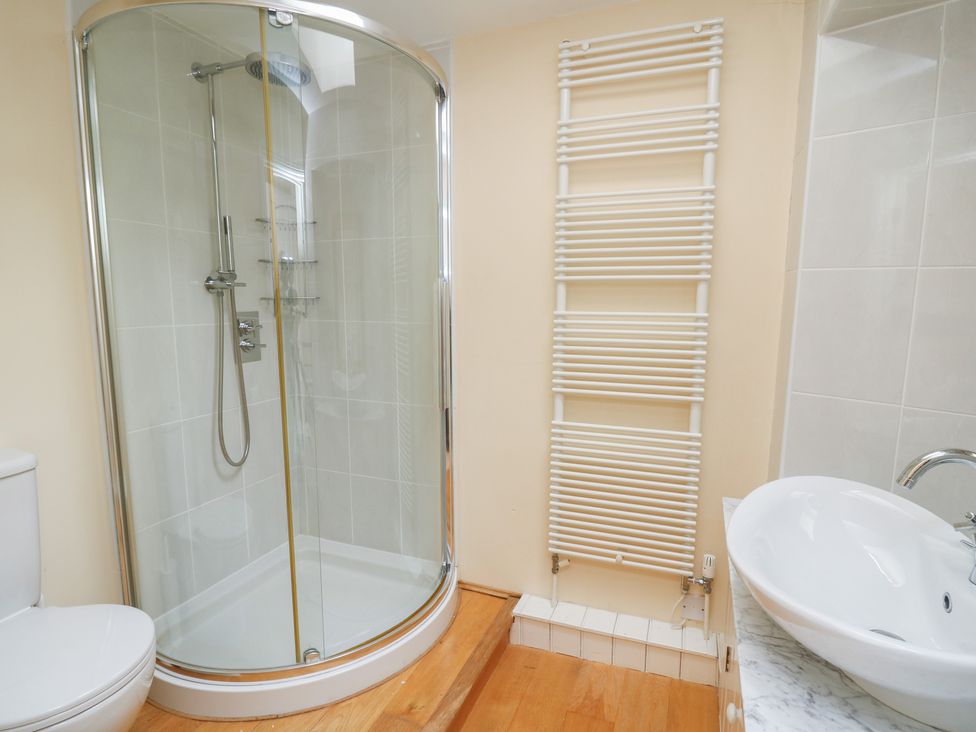 A bathroom with a corner shower enclosure toilet sink and a wall-mounted radiator at Pen y Graig in Aberporth