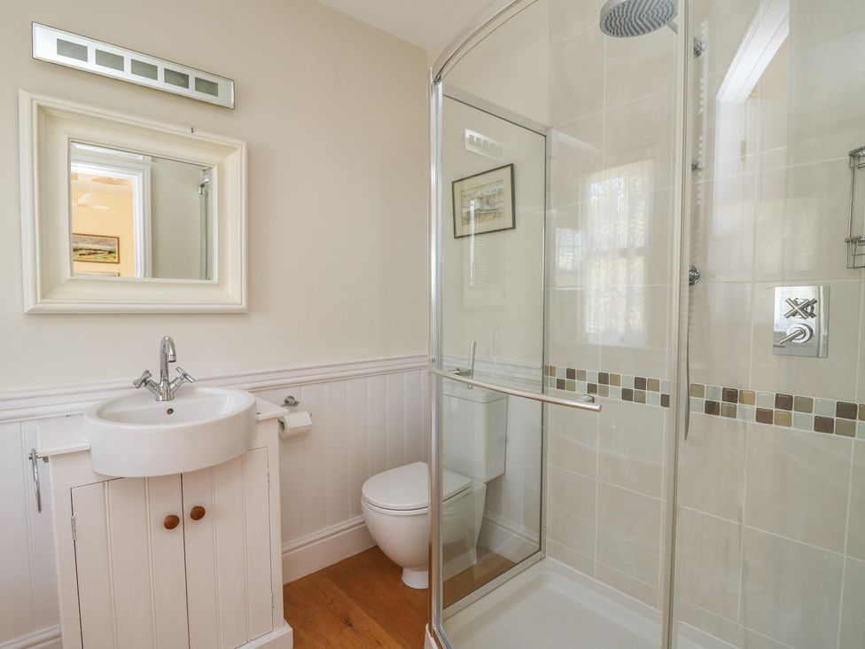 A bathroom with a sink cabinet toilet and glass shower enclosure at Pen y Graig in Aberporth