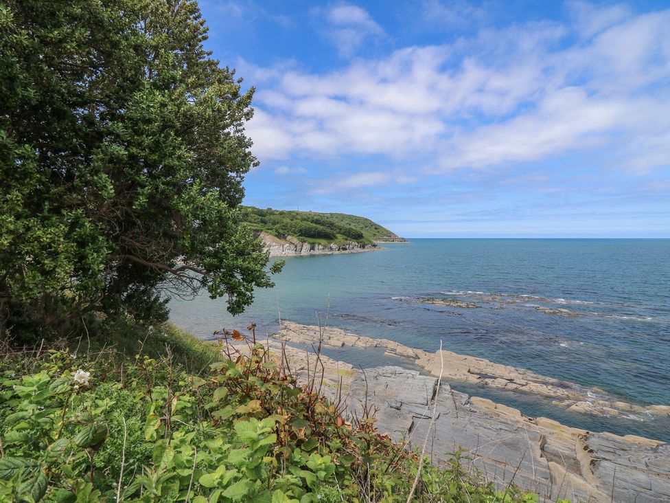 A coastal scene with green vegetation rocky shore and blue sea at Pen y Graig in Aberporth