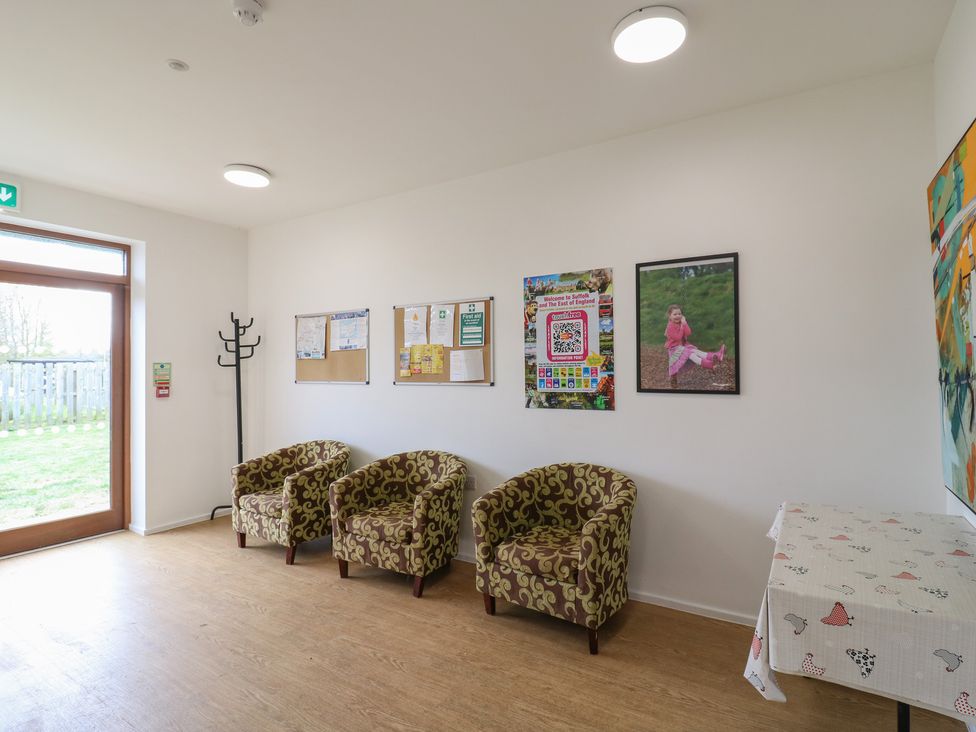 A waiting area with three patterned armchairs a coat rack bulletin boards and posters on the walls at Daisy Cow Shed 1 in Easton near Campsea Ashe
