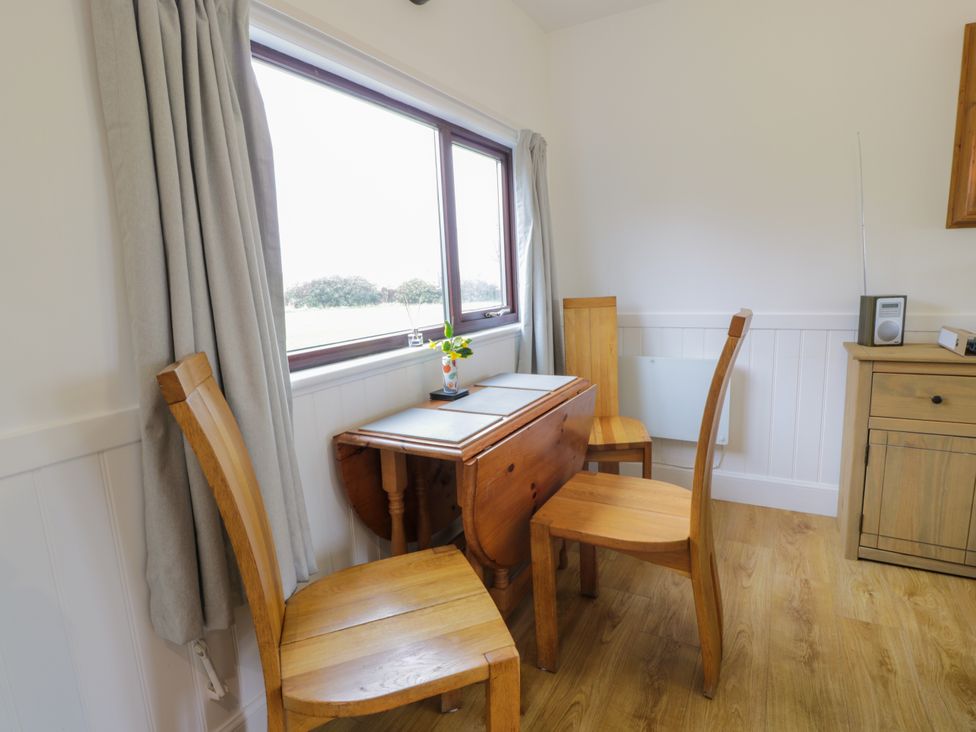 A dining area with wooden chairs and a drop-leaf table near a window at 3 Laigh Isle Isle of Whithorn near Kirkcudbright
