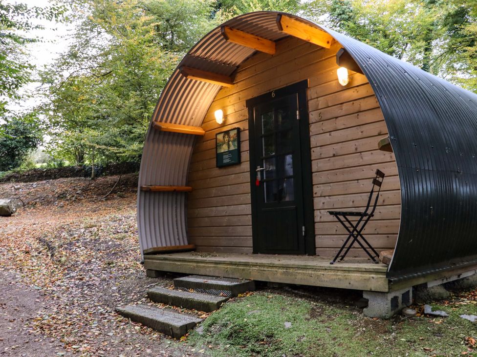 An outdoor wooden pod with a curved metal roof a black door and a folding chair on the porch at Ballybeg Pod 8 Ballybeg near Tinahely County Wicklow