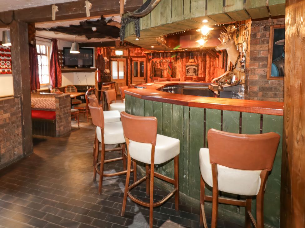 A bar area with high chairs and wooden paneling at Bear Claw Lodge in Castlerock